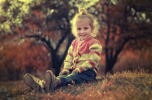 mała dziewczynka siedzi usmiechnięta w trawie