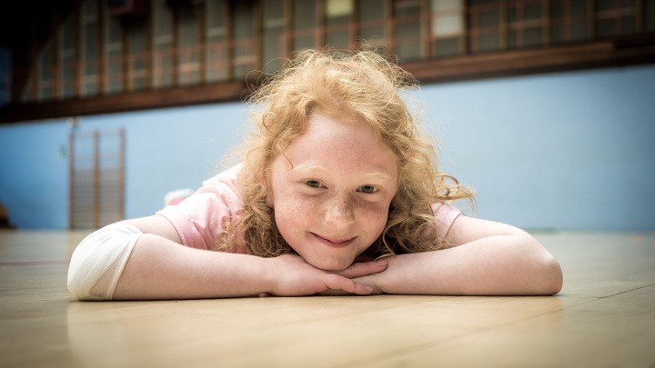 szczęśliwa, piegowata dziewczynka leżąca na podłodze w sali gimnastycznej