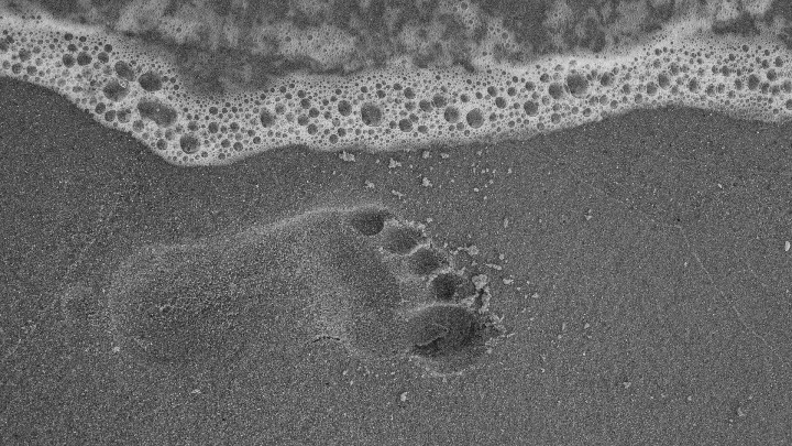 ślad stopy odciśnięty na morskim, mokrym piasku
