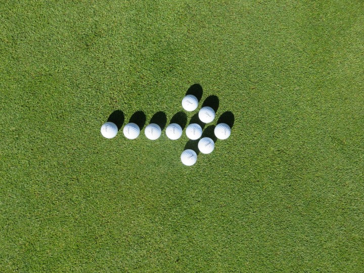 biała strzałka na polu golfowym ułozona z piłeczek golfowych